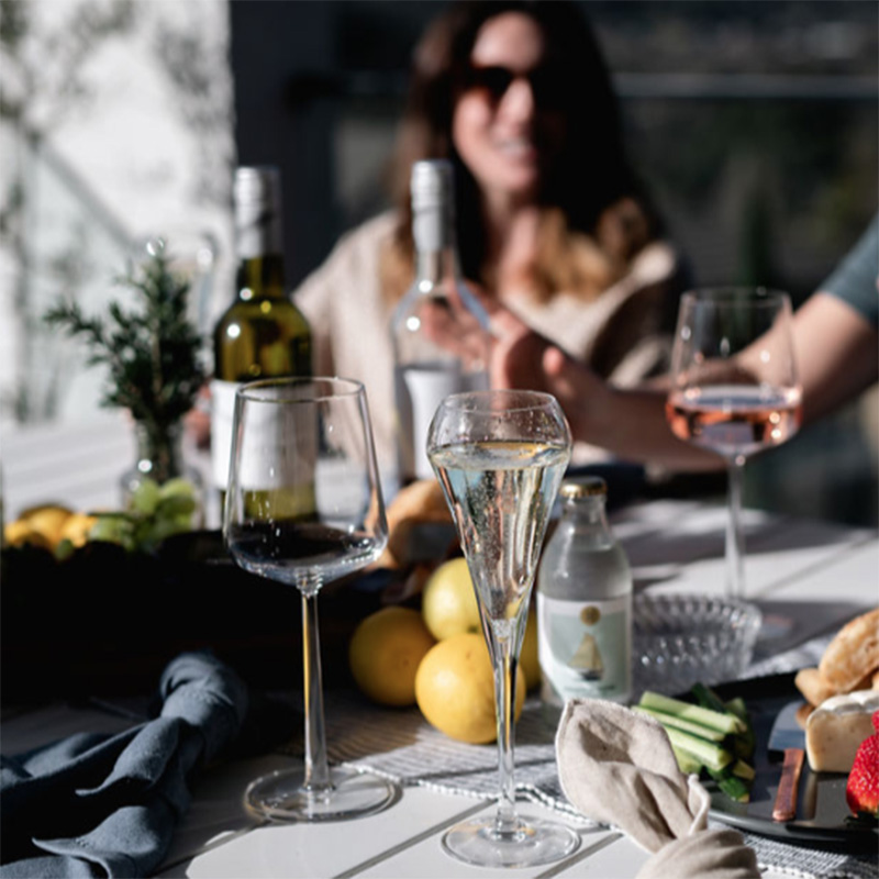 People drinking wine a a table full of food and drinks